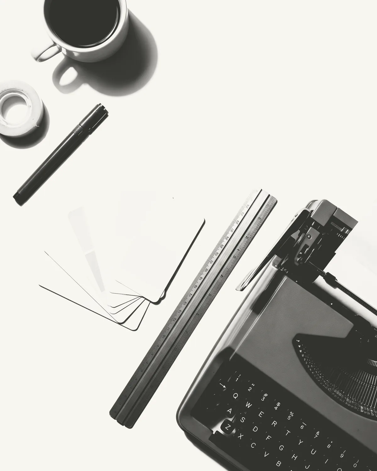 escritorio visto desde arriba con una máquina de escribir, una regla y un café